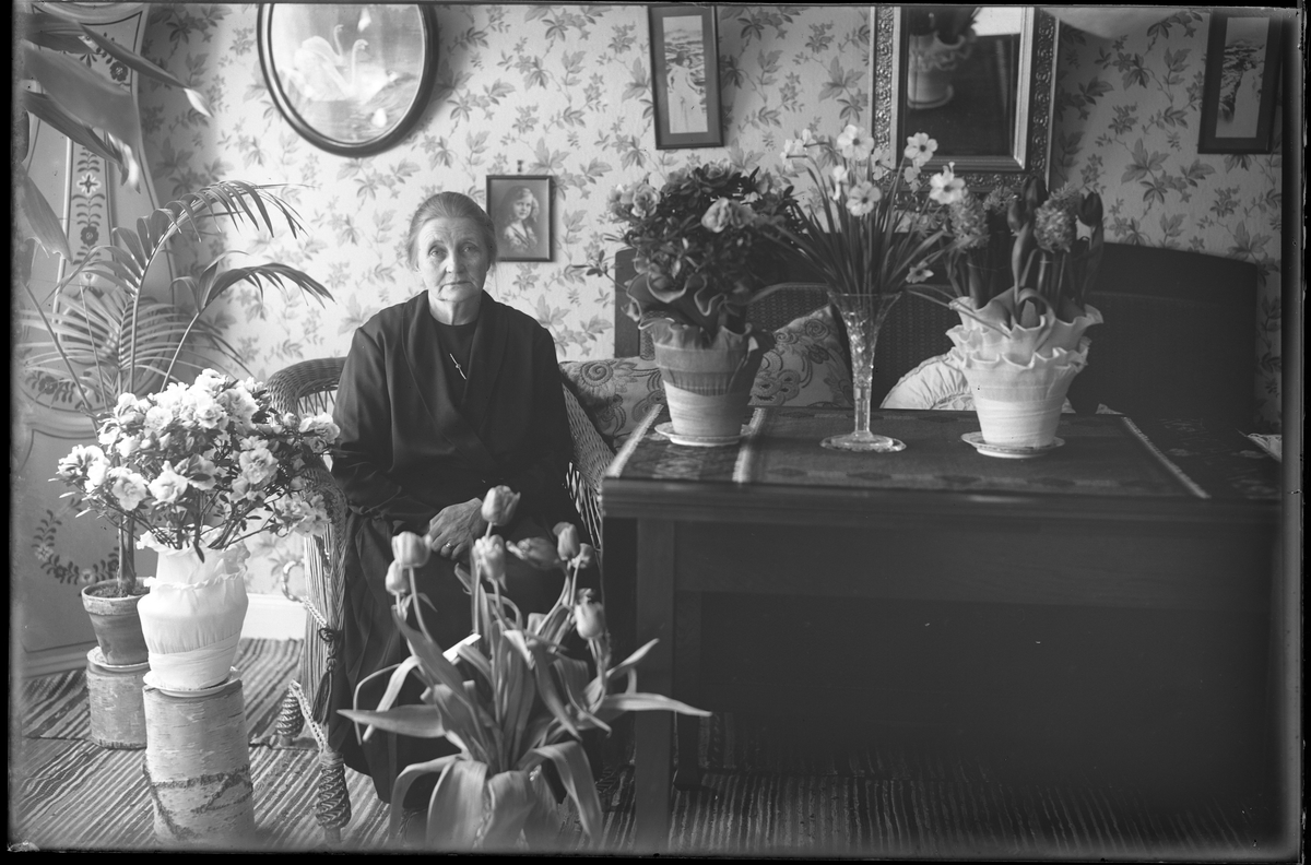 Fru Pettersson fotograferad i ett finrum tillsammans med blommor i samband med sin 65årsdag.