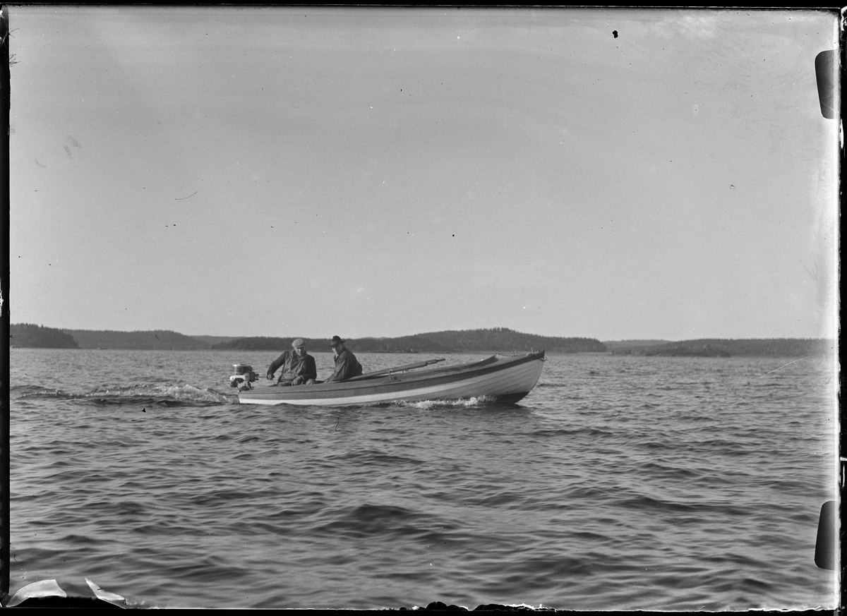 Två män sitter i en träbåt ute till sjöss. I fotografens egna anteckningar står det "Olles båt".
Båtens ägare Olle Pettersson.