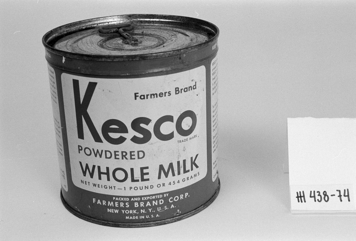 Boks, blikk, falset. Sylinderform . Nøkkel metall, åpner, loddet til lokk. Karside hvit/grønn/brun.
Mrk. bruksanvisning på engelsk . "Kesco", Farmers Brand", "POWDERED WHOLE MILK",  "MADE IN USA". Rustflekker. Uåpnet boks, inneholder tørrmelk.