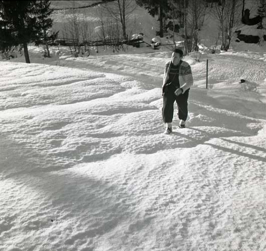 En man vandrar över en snöig slänt och hans kropp kastar skuggor på skarsnön, 1947.