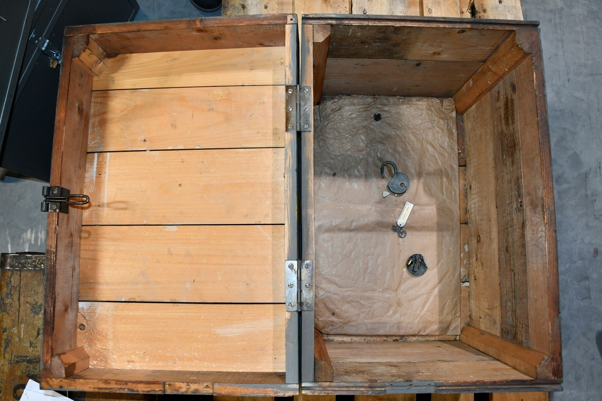 Kasse laget i tre med påmalte bokstaver og tall på lokket og to av sidene. Kassen er uten arkivinnhold, men inneholder en ødelagt nøkkellås og nøkkel som er merket "Arkiv - London".