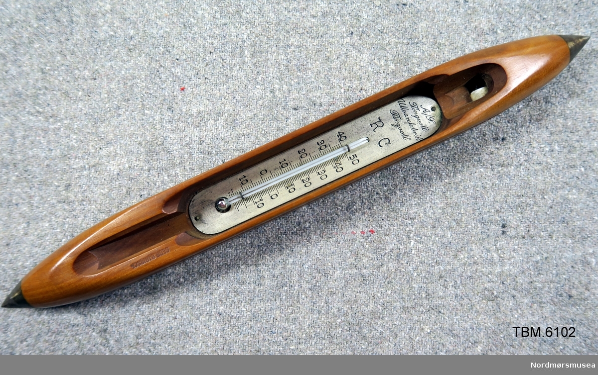 Fin polert vevskei med eit termometer i rommet der spolen skal vere.
Reklame for Tingvoll Ullvarefabrikk