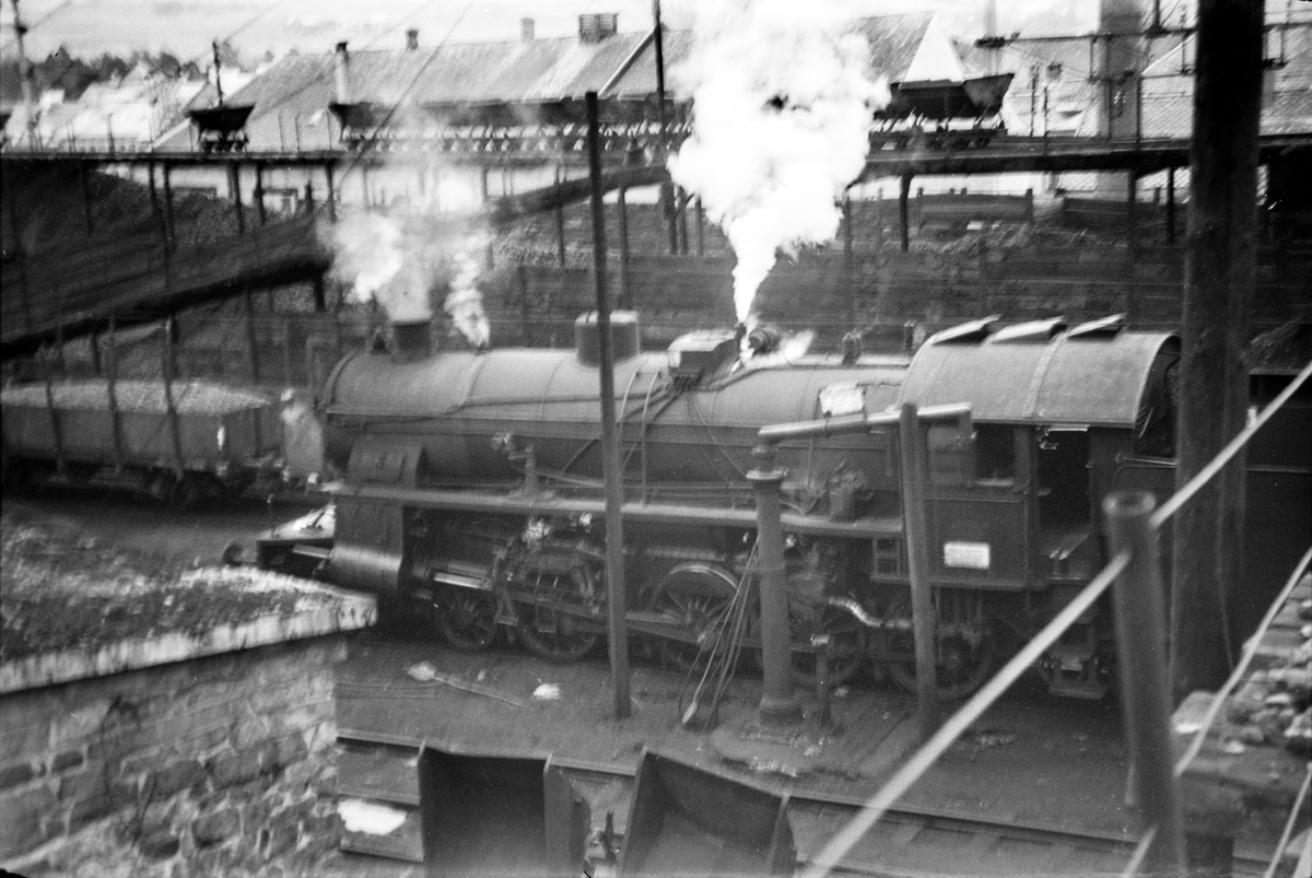 Damplokomotiv type 31b nr. 419 ved lokomotivstallen på Voss stasjon. I bakgrunnen vagger som ble benyttet til transport av kull til damplokomotivene.