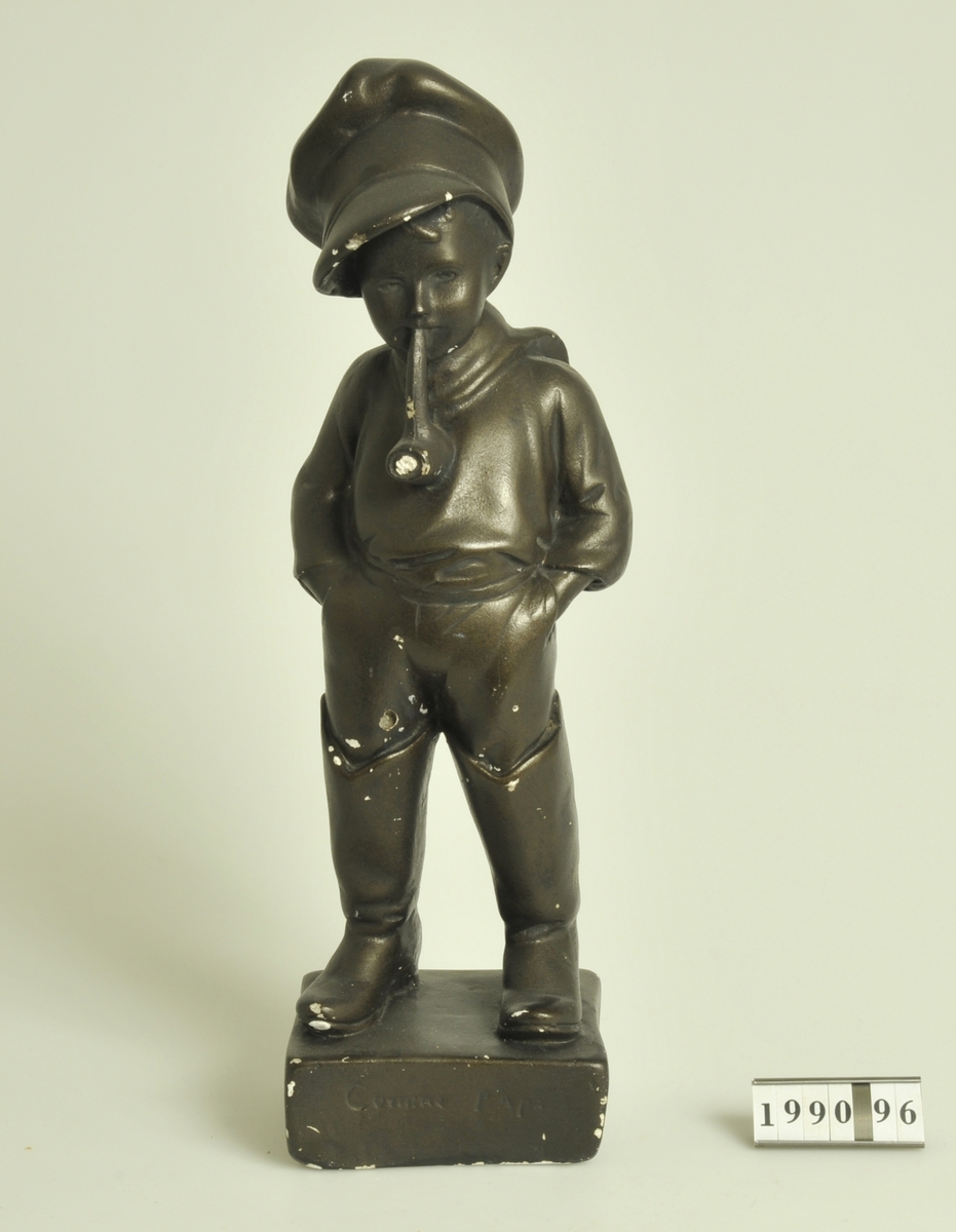 
Statyett föreställande piprökande pojke:: "Comme papa." Bronsfärgad.
