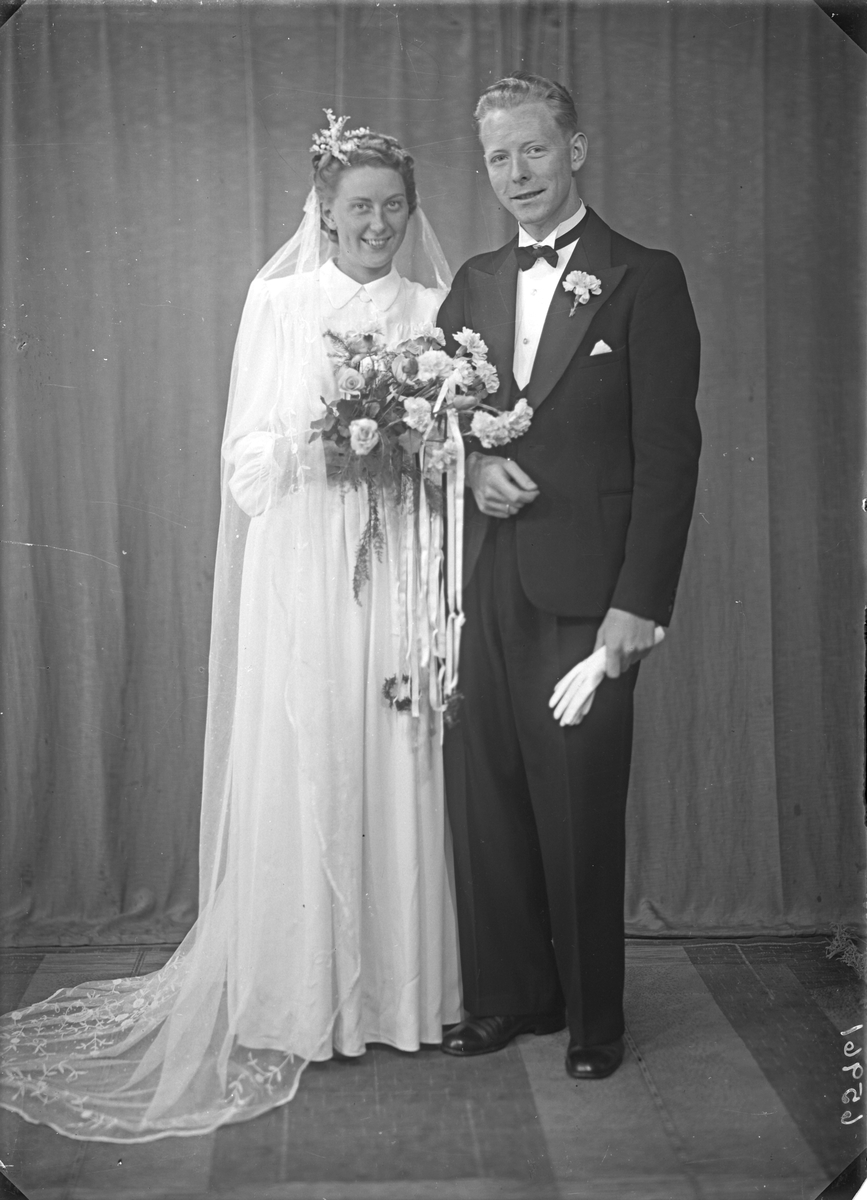 Brudebilde. Ung kvinne i lys brudekjole og ung mann i mørk dress med tverrsoversløyfe. Brudepar. Bestilt av Per Velde. Haraldsgt.