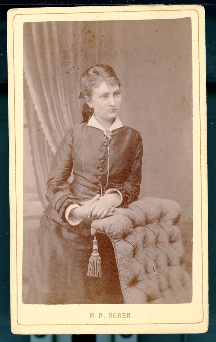 Kabinettsfotograf: Ellen Mozart, en ung kvinna som står lutad mot en fåtölj.