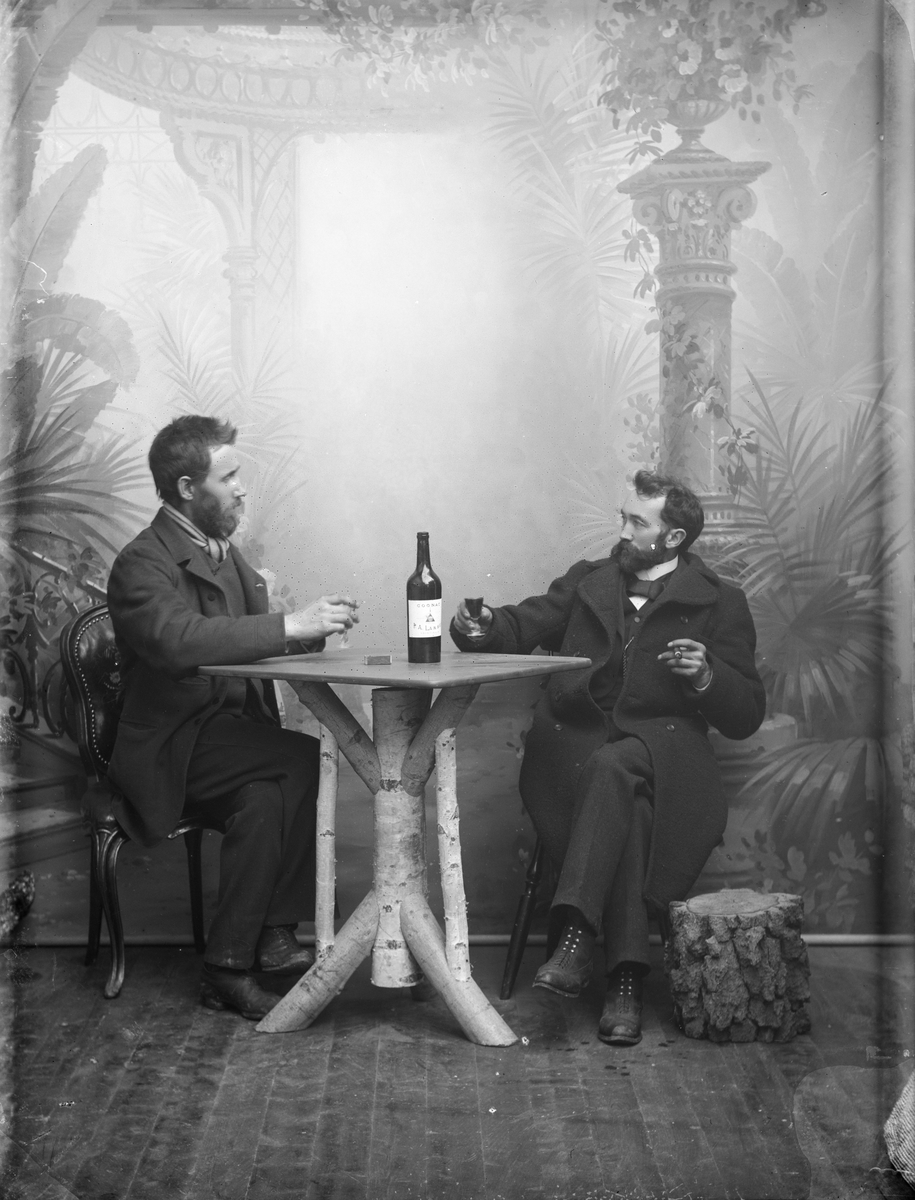 Beskrevet som P. Kaas´s gruppe. To menn tar en drink. En flaske med Larsen cognac på bordet.