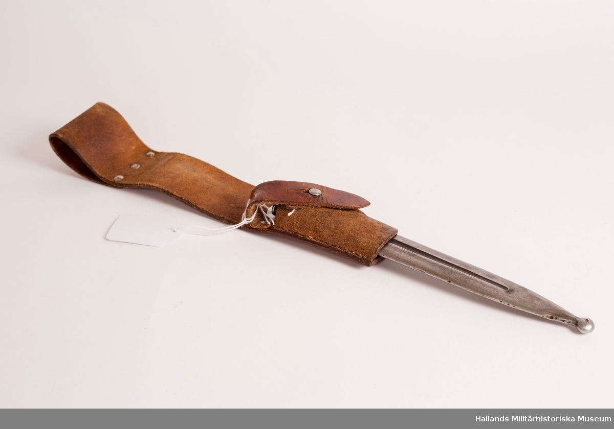 Bajonetthylsa för knivbajonett m/1896. Tillverkad i brunt läder. Baljan fästes i hylsan med hjälp av läderrem och mässingsknopp.