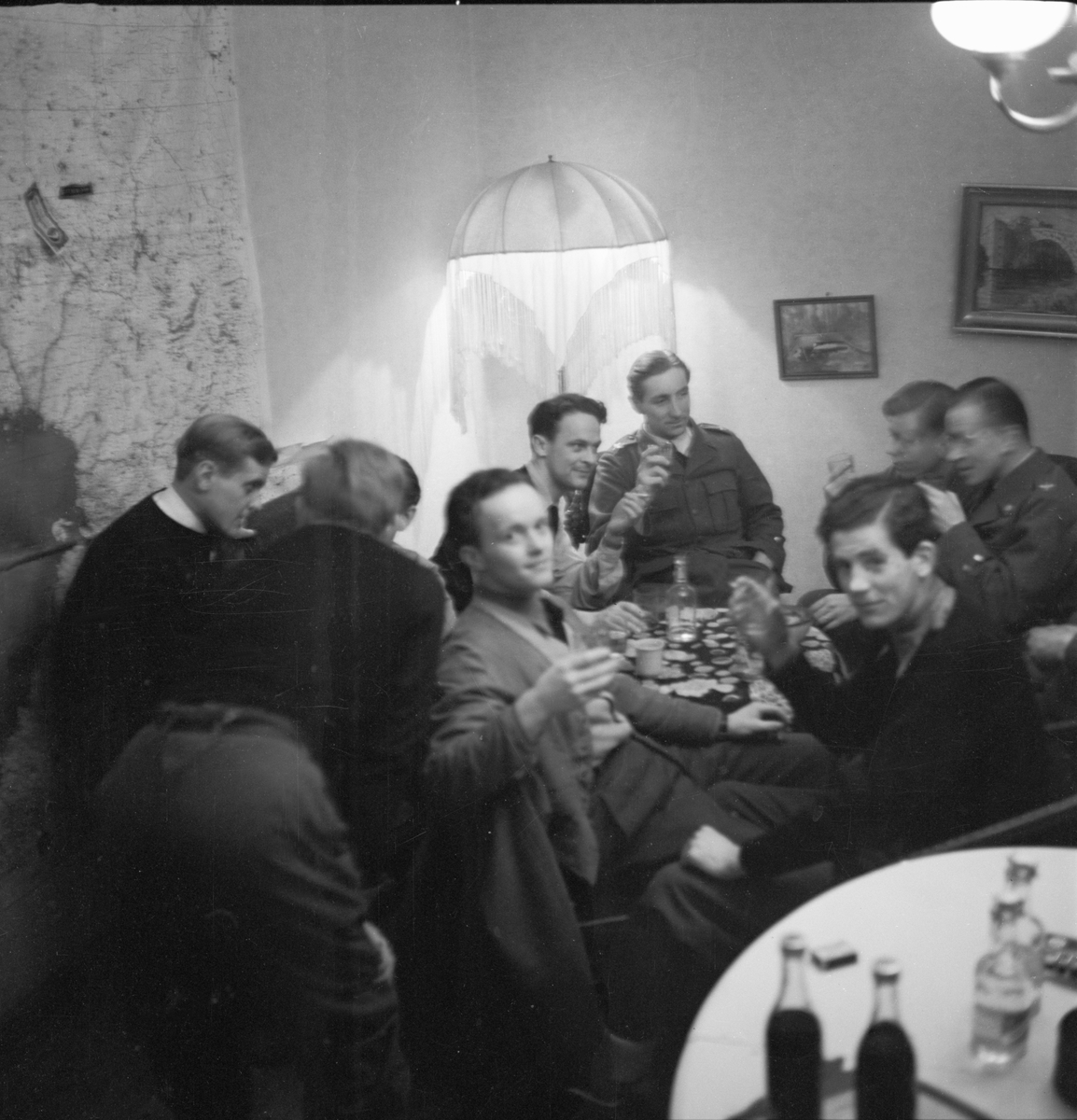 Samkväm på förläggning vid Svenska frivilligkåren i Finland, F 19. Gruppfoto av militärer sittande runt ett bord.