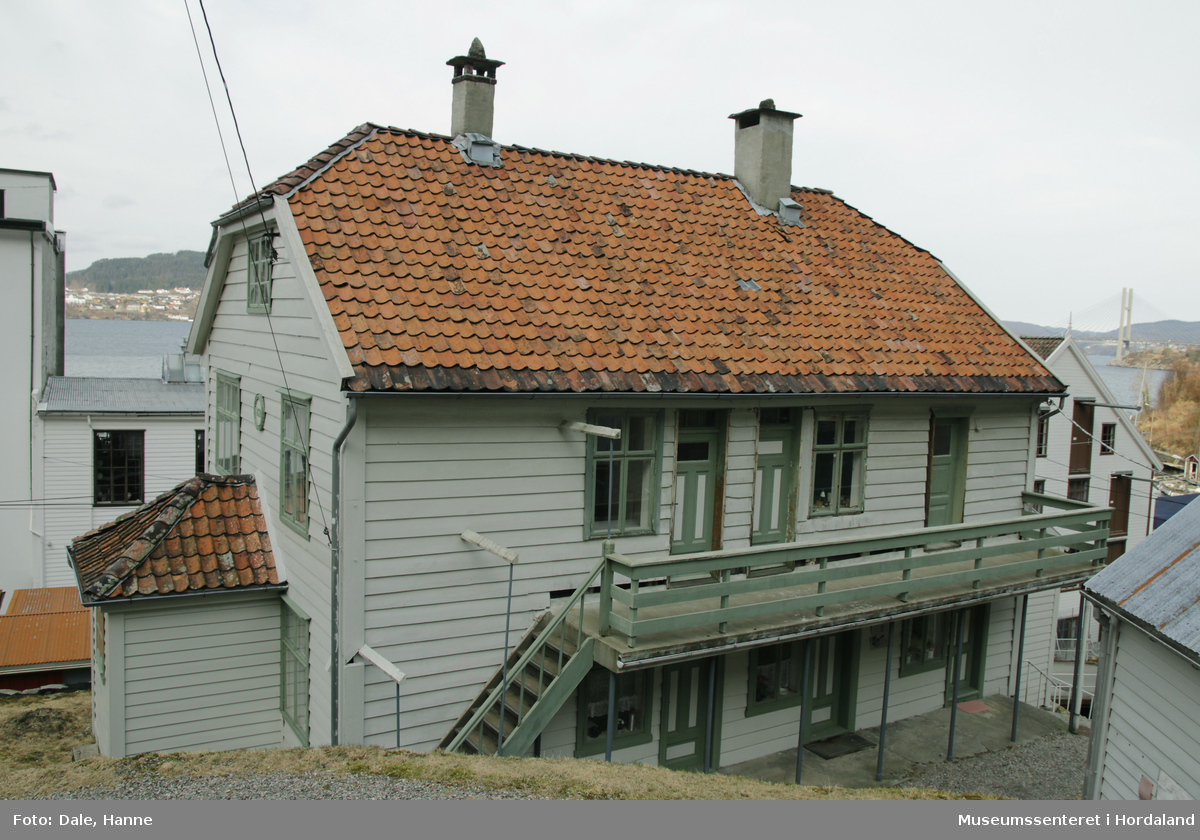Den første arbeidarbustaden til Salhus Tricotagefabrik (1859-1989), bygd året etter fabrikken. Opphavleg inndelt i seks leilegheiter og sovesalar.