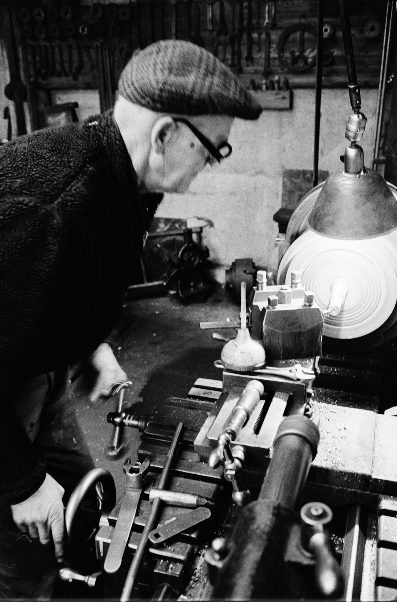 Fabrikör Karl-Gustav Johansson reparerar en pelletskvarn och arbetar vid stora svarven, Enköpings Kvarnstensfabrik, Bangårdsgatan 13, Enköping, Uppland 1984