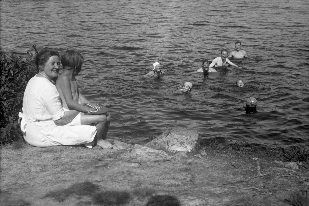 Flere mennsker bader i Lisjøen,noen sitter på land.