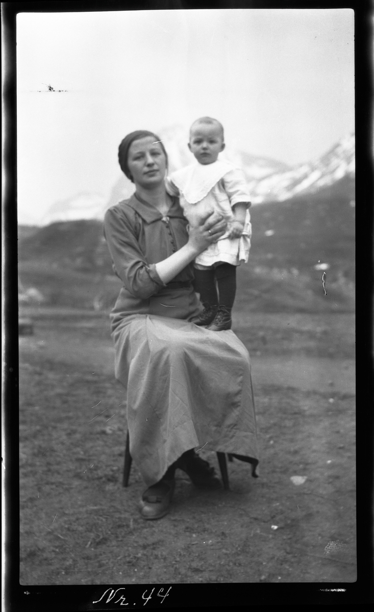 Portrett av en kvinne med barn, tatt utendørs med fjell i bakgrunnen.