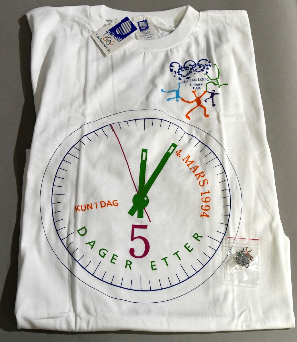 T-skjorte med klokke der viserne viser  kl. 12.05. På høyre bryst  knuste olympiske ringer og etterligning av ol-piktogrammer.