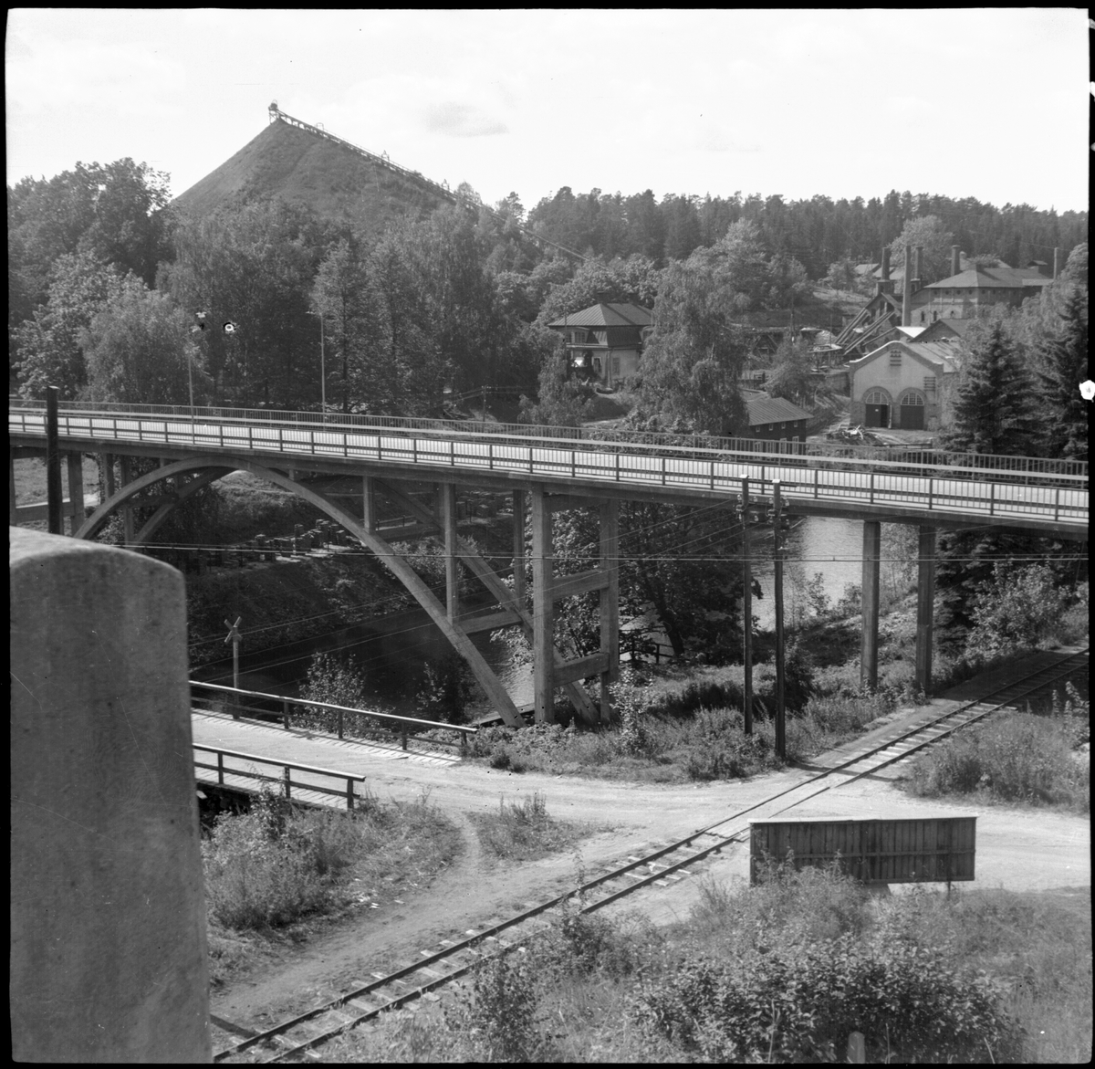 I förgrunden syns landsvägsbron, som byggdes 1934. I bakgrunden slagghögen och delar av järnbruket.
