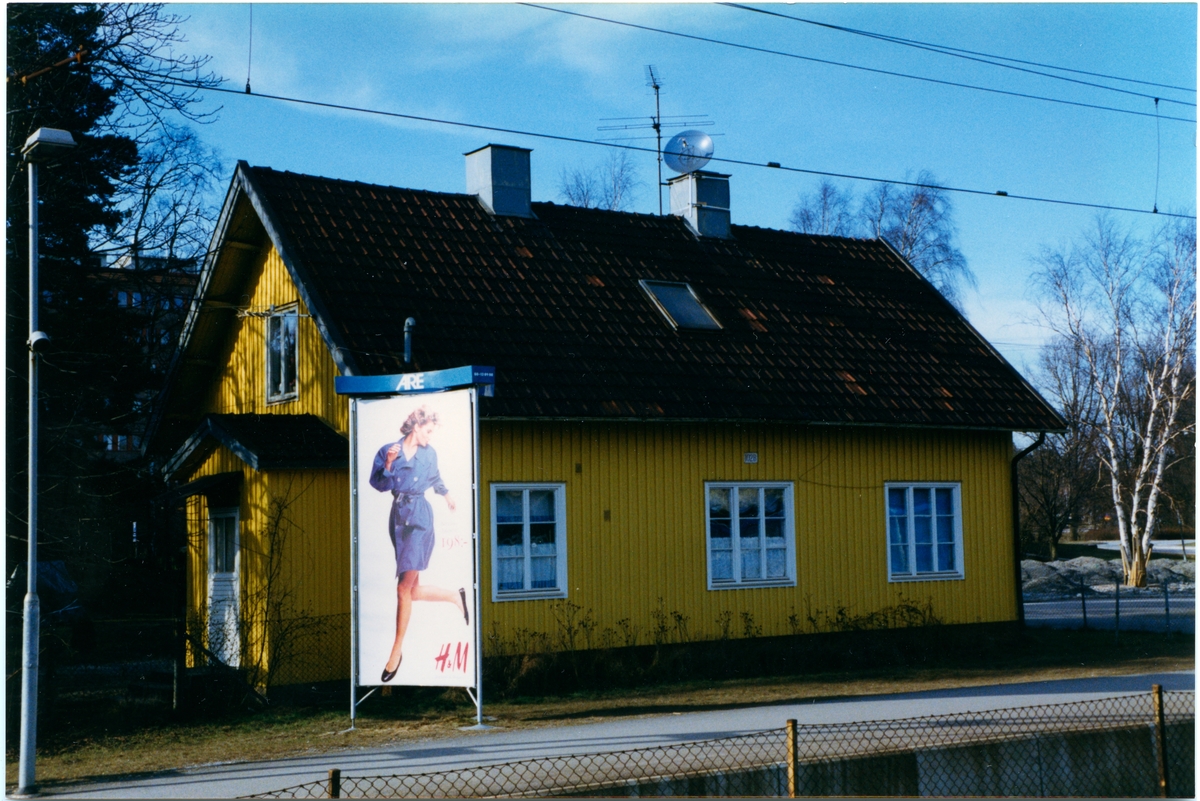 Stationshuset i Roslags Näsby med en reklampelare på plattformen.