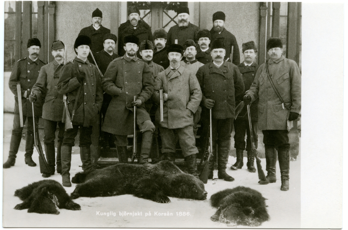 Kungliga björnjägare framför trappan till herrgården vid Korså Bruk. 
Prins Eugen och kronprins Gustaf  med jaktsällskap poserar för fotografen, vintern 1886.