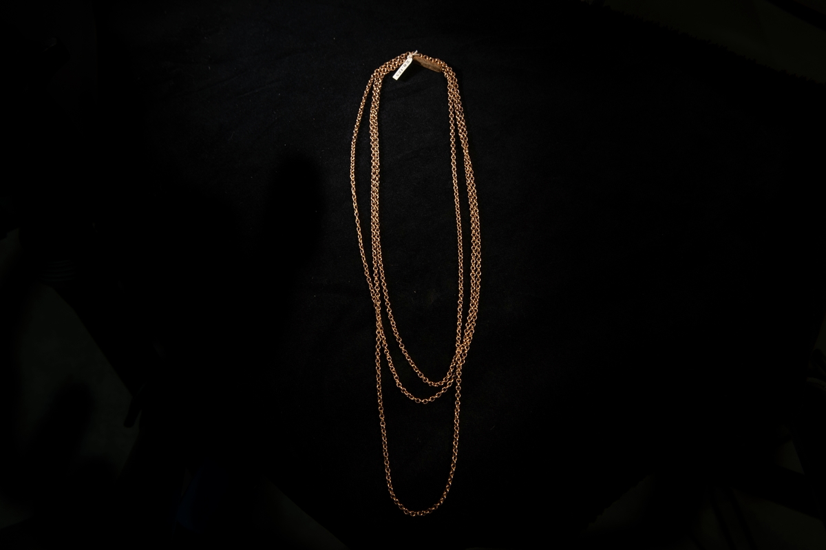 Lång halskedja av guld (enkel modell). Sticklås med graverad dekor av slingor.