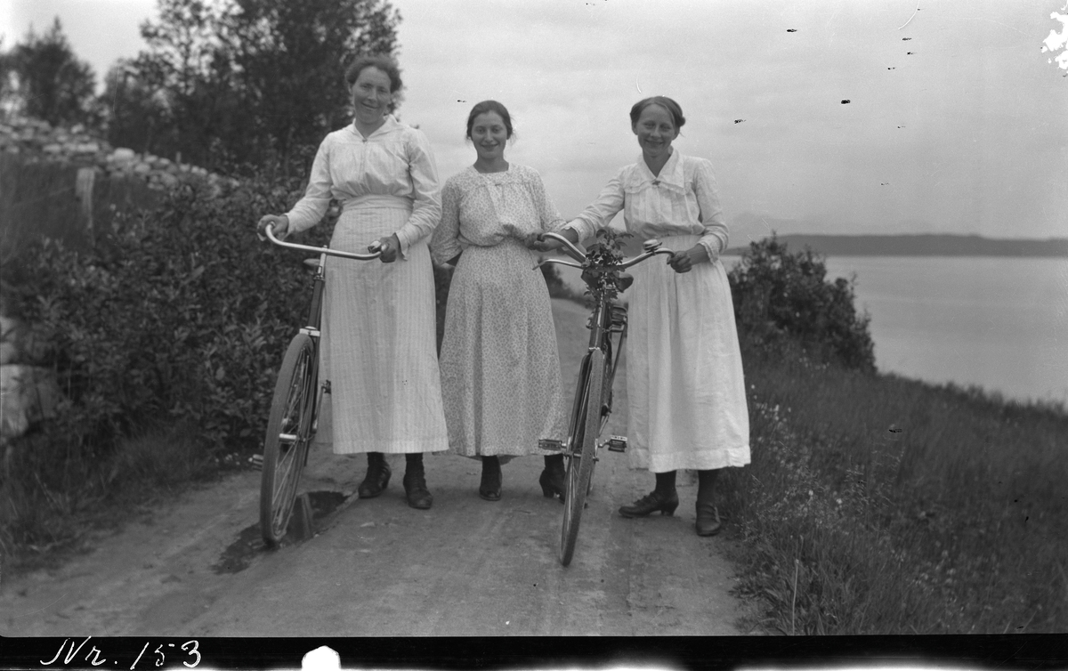 Tre kvinner på bygdevei. To av dem har sykkel.