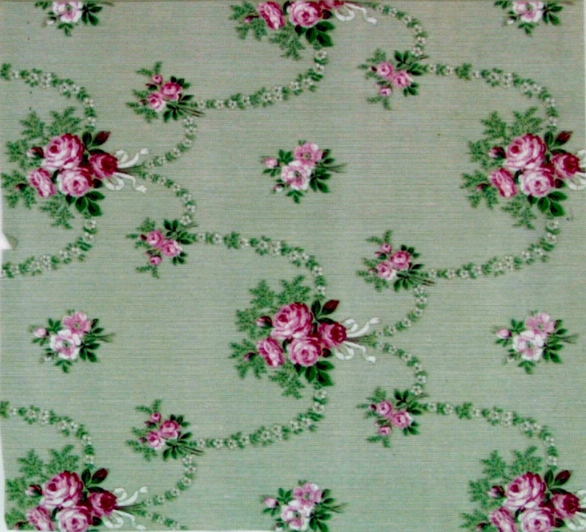 Rosenbuketter och girlanger i diagonalupprepning på en bakgrund dekorerad med ett litet vitt randmönster. Tryck i vinrött, vitt och grönt samt i två rosa nyanser. Ljusgrönt genomfärgat papper.