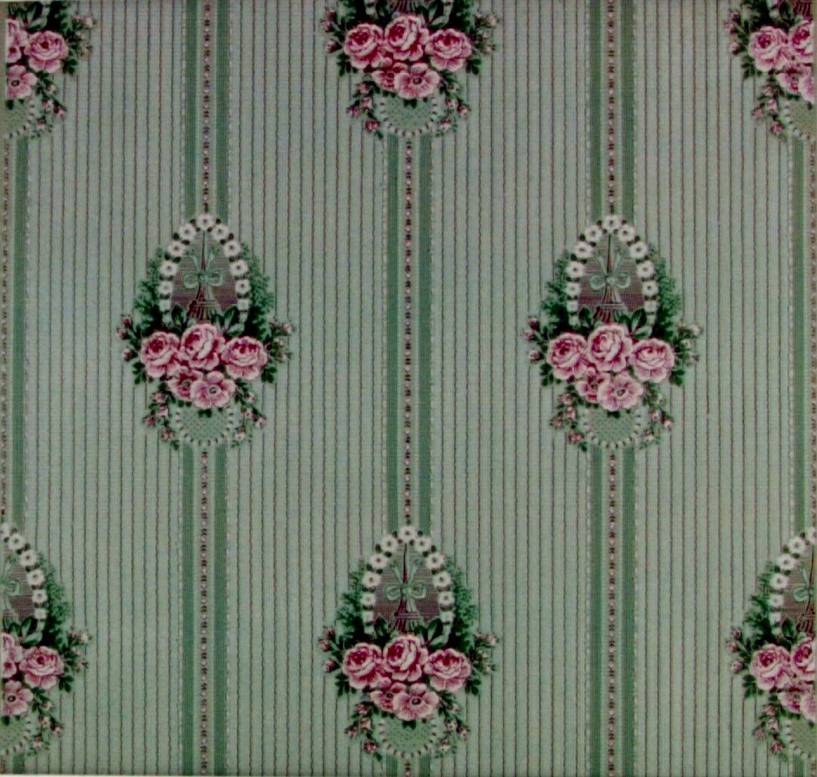 Randmönster med spetsbårder och rosenbuketter med girlanger i diagonalupprepning. Tryck i rosa,vinrött och grönt på ett ljusgrönt genomfärgat papper. Textilimiterande bakgrund.