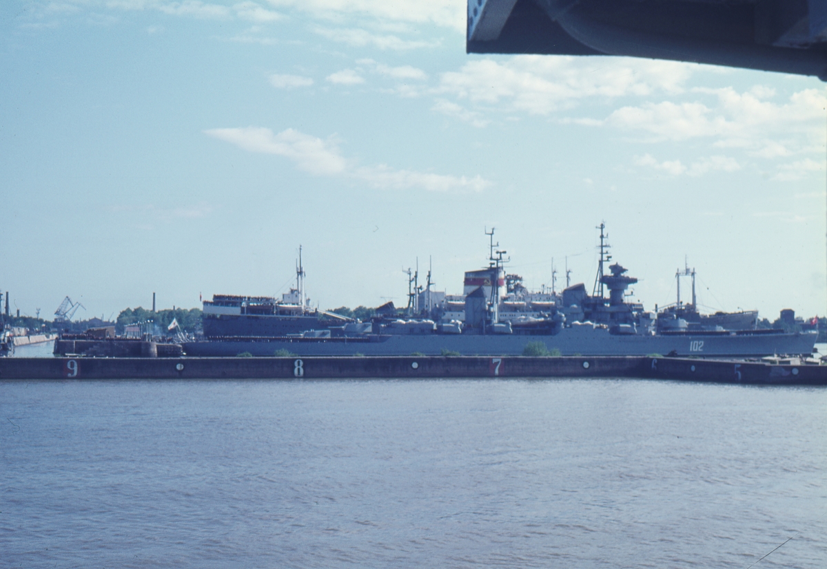 Bilden visar den ryska kryssaren Sverdlov i hamnen i St Petersburg. På däcket av kryssaren och ett bakomliggande örlogsfartyg har manskapet tagit uppställning.