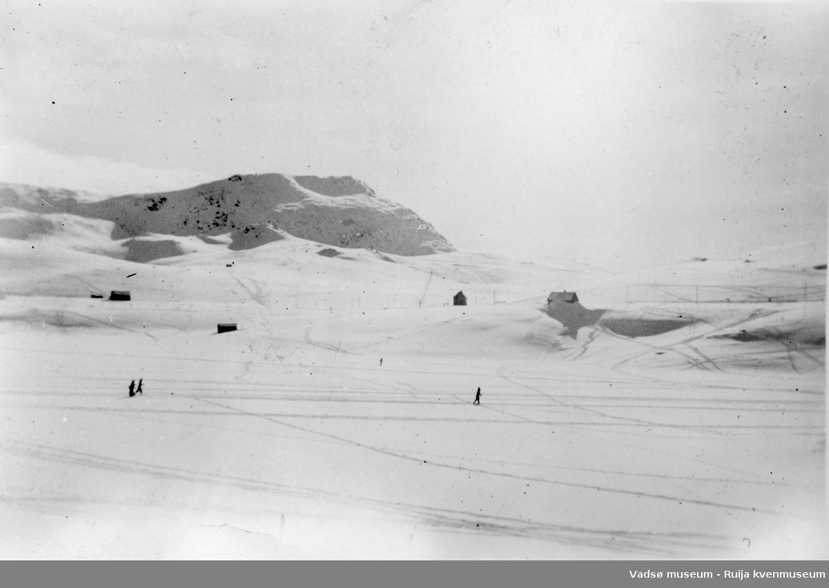 Tre personer på ski på Storvannet. I bakgrunnen ses flere hytter.