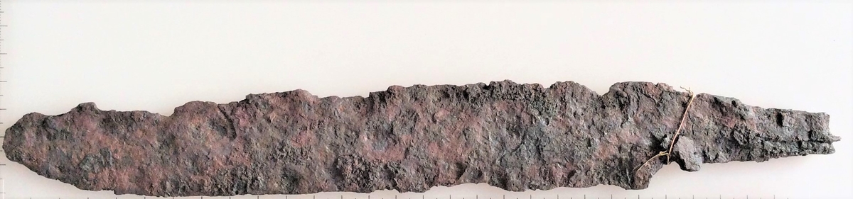 Sverdblad eller stor kniv av jern fra yngre romersk jernalder.  Funnet i en kvinnegrav på Vestby under Evang i 1885