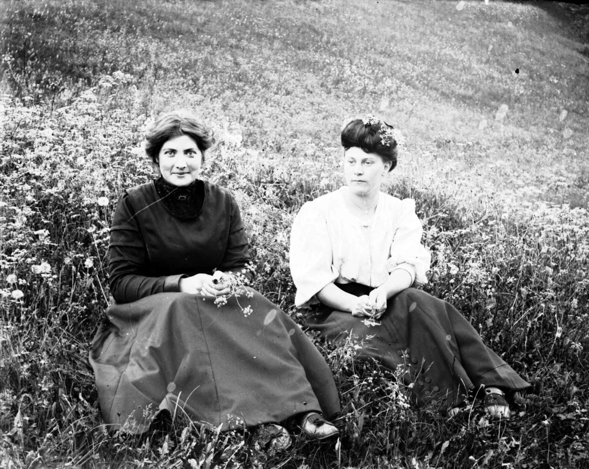 To unge kvinner sitter i en eng. Kvinnen til høyre er oppgitt å være Henriette Voldbakken