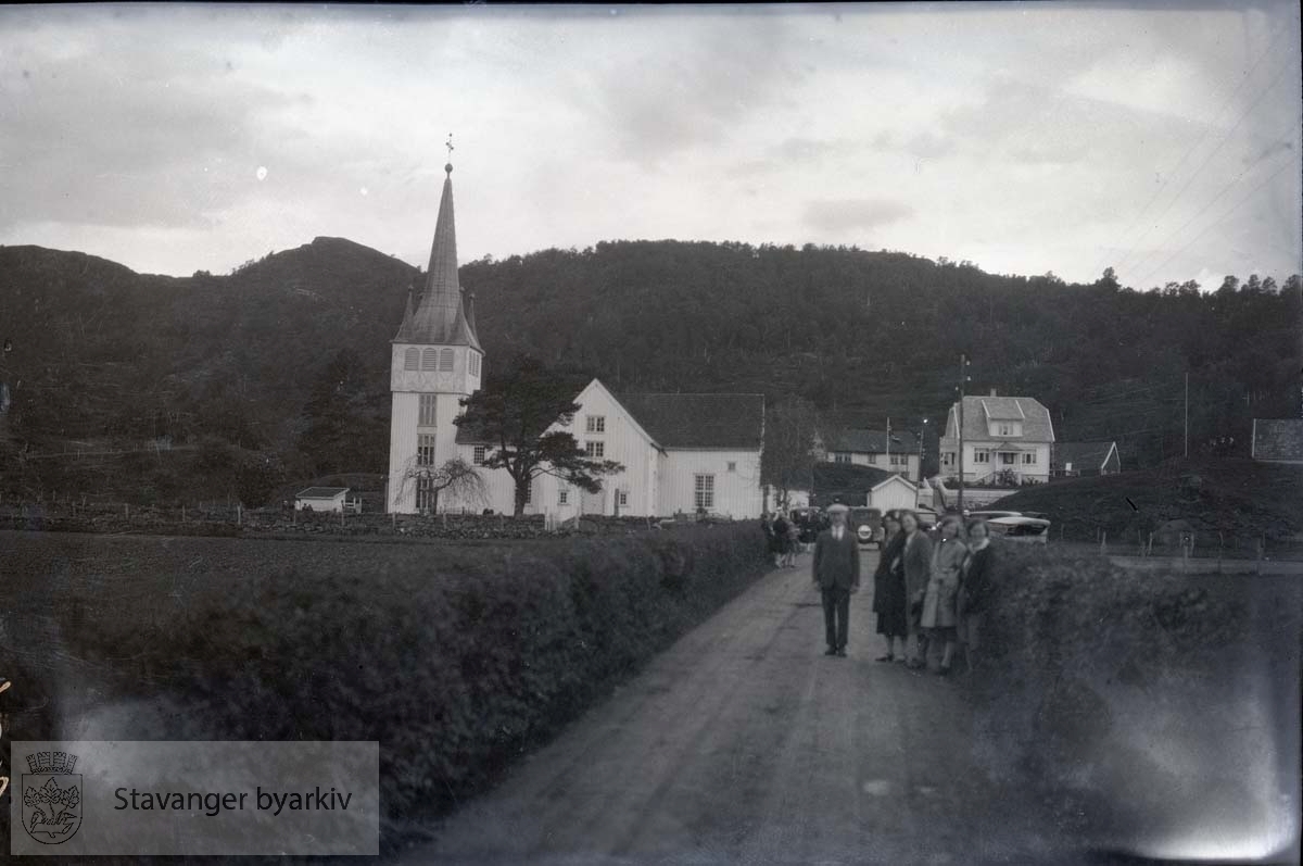 En mann og fire kvinner på landevei foran kirke