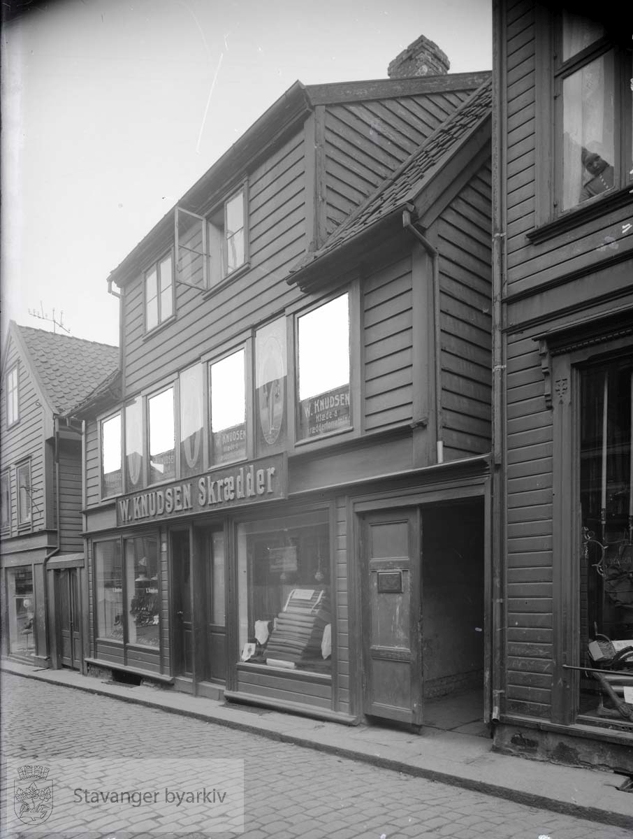 I første etasje Leonhard Knudsens skomakerforretning. I andre etasje Wilhelm Knudsens skredderforretning.