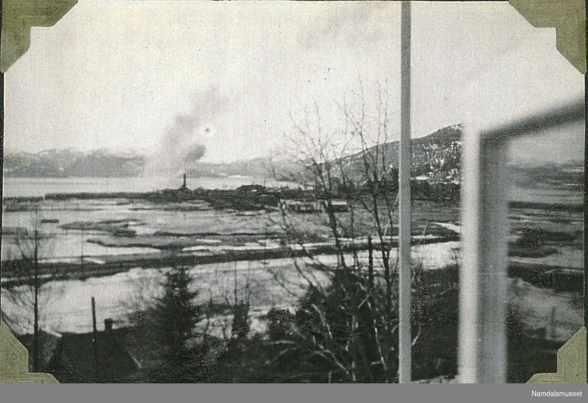 Utbombet Namsos sett fra Bjørum. Fjorden i bakgrunnen. En båt brenner på fjorden.