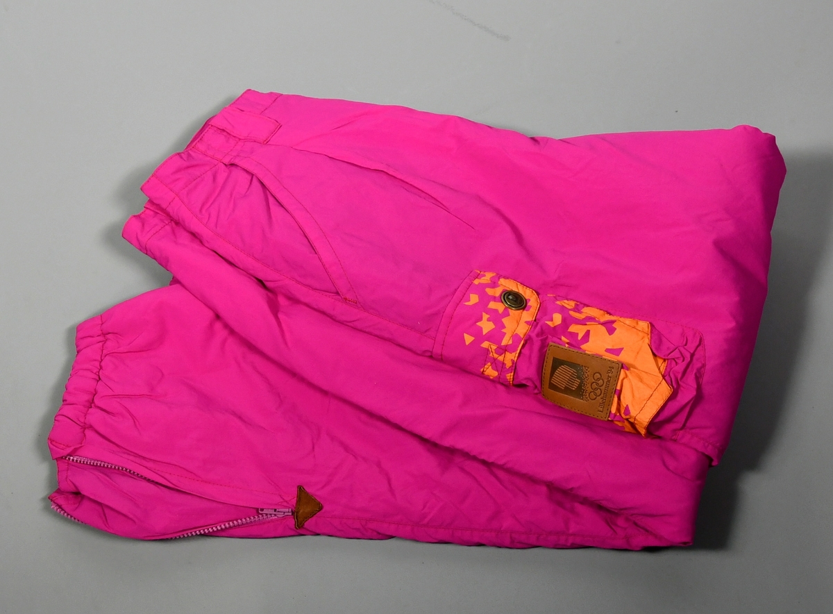 Rosa, vattert vinterbukse med glidelås nederst ved beina. På det høyre låret er det en lomme med krystallmønster i oransje, med skinnmerke med logo for Lillehammer '94. Buksen har fór med krystallmønster i blått og lilla.
