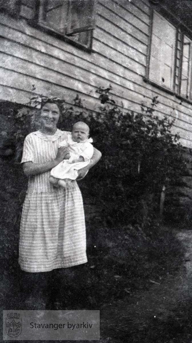 Kvinne med barn foran bolig.