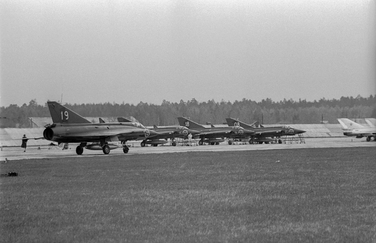 Fem flygplan J 35 Draken uppställda på landningsbana på sovjetisk flygbas. Flygplan märkt nummer 19 i förgrunden. Vid Kungliga Upplands flygflottiljs besök vid sovjetisk MiG-21-bas den 16 mars 1972.