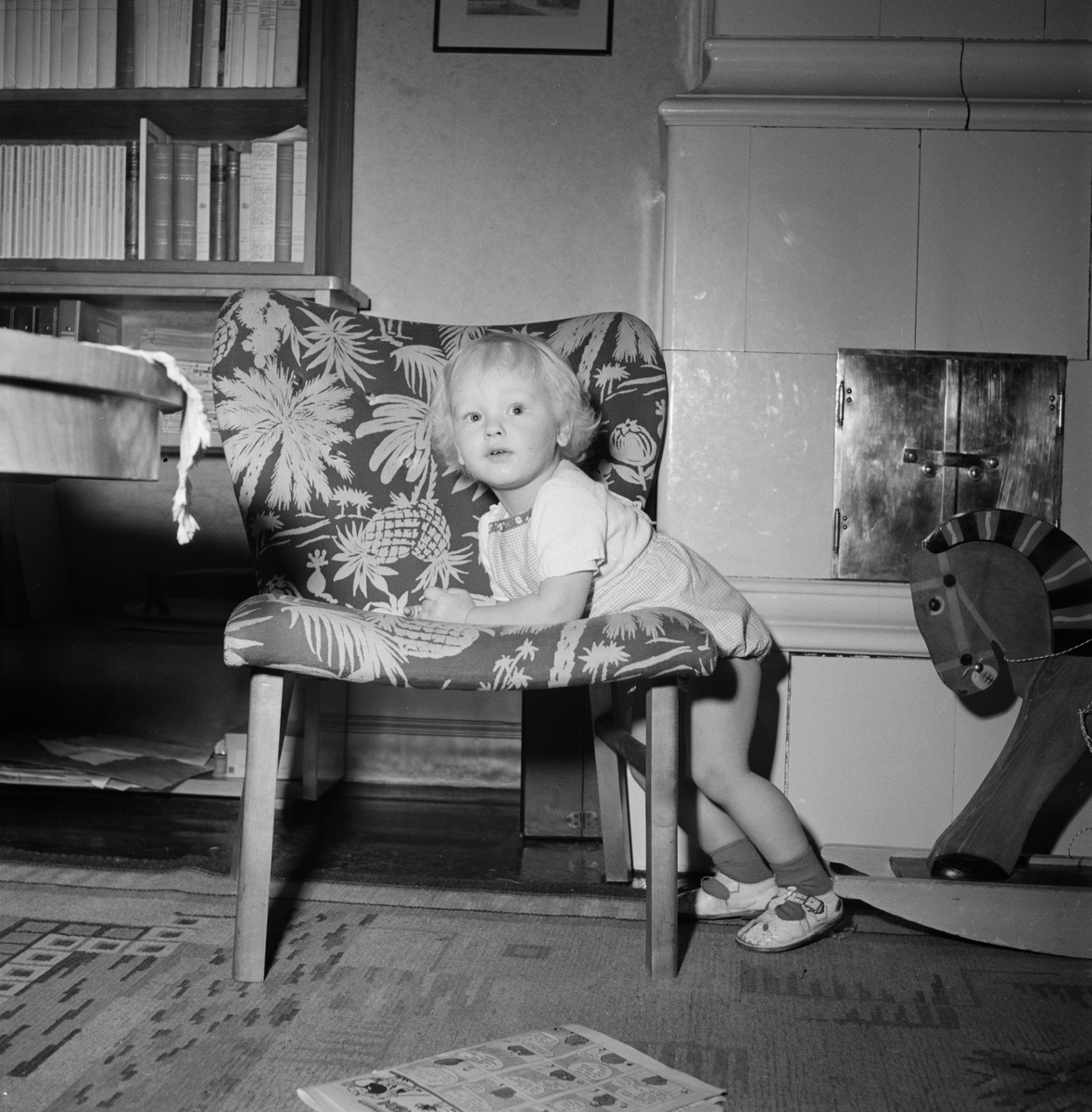 Pojke står vid fåtölj, Uppsala 1952