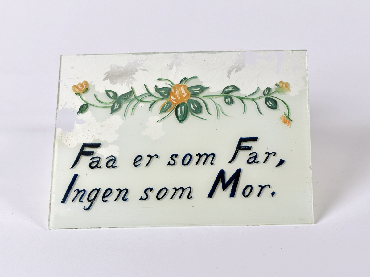 Lite bilde. Påmalt på glasset: " Faa er som Far, Ingen er som Mor". Blomstermotiv over teksten.