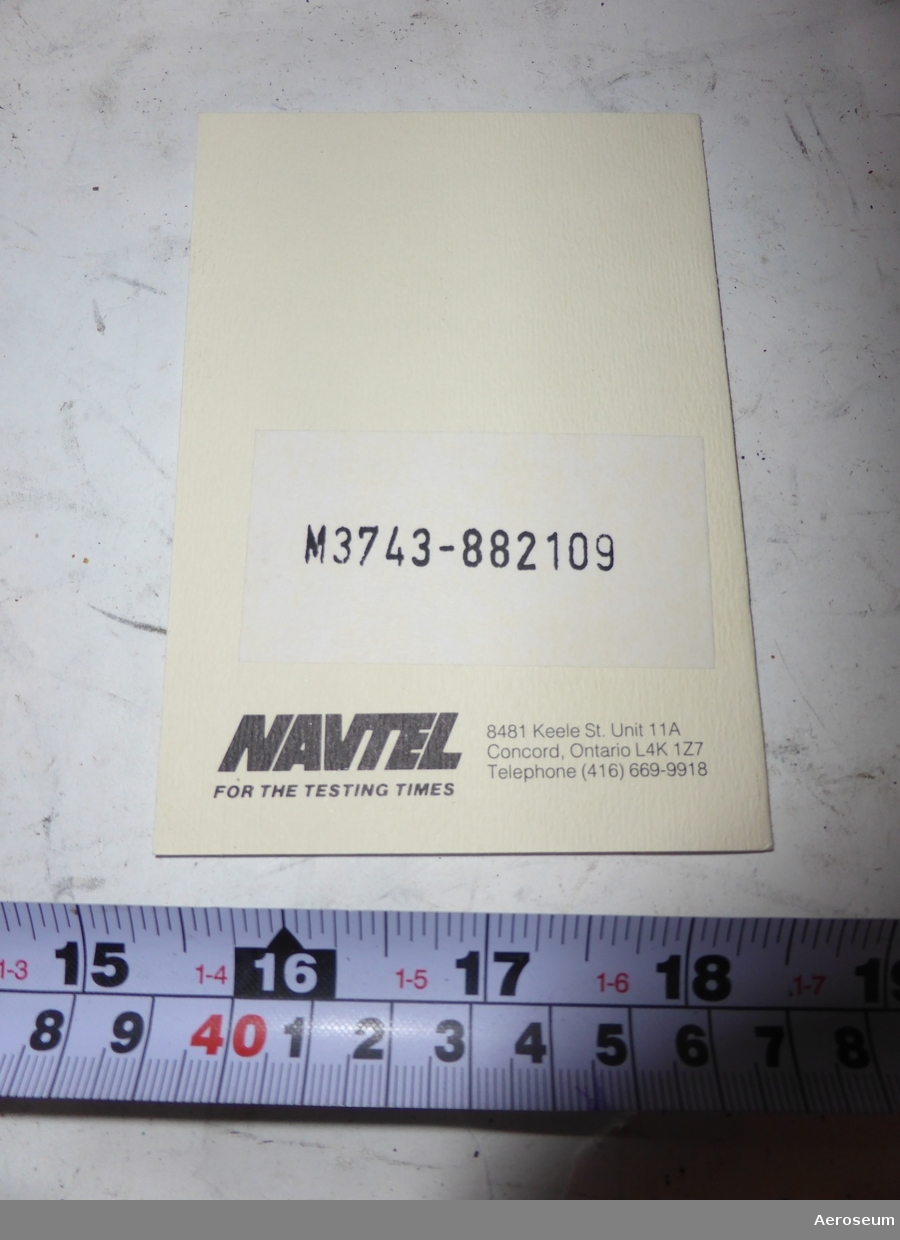 En pappkartonglåda med ett gränssnittprovdon för datakommunikation i. I lådan finns även en bruksanvisning, och ett papper där det står: "Navtel warranty registration card".