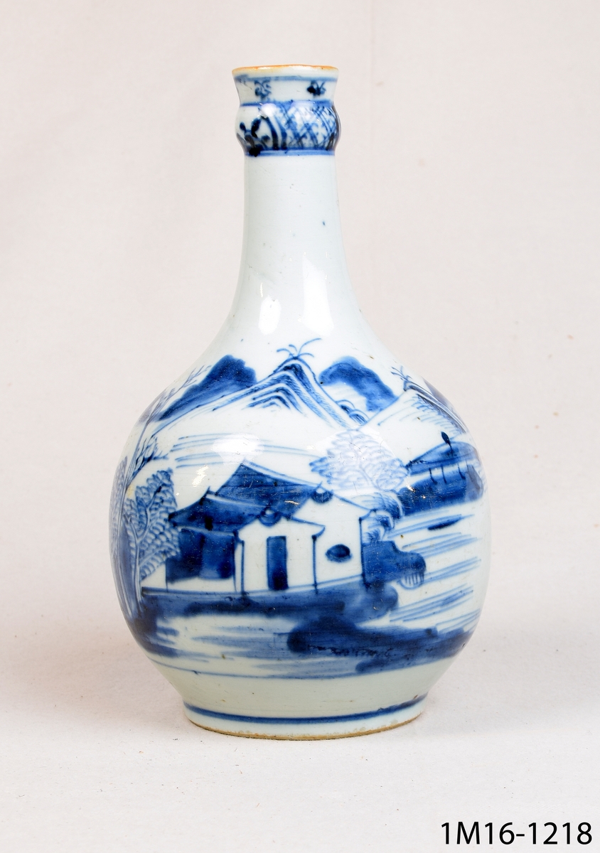 Rund vas i flaskform eller rund karaff med vit glasyr och blå handmålad dekor bland annat föreställande landskap. Kinesisk.