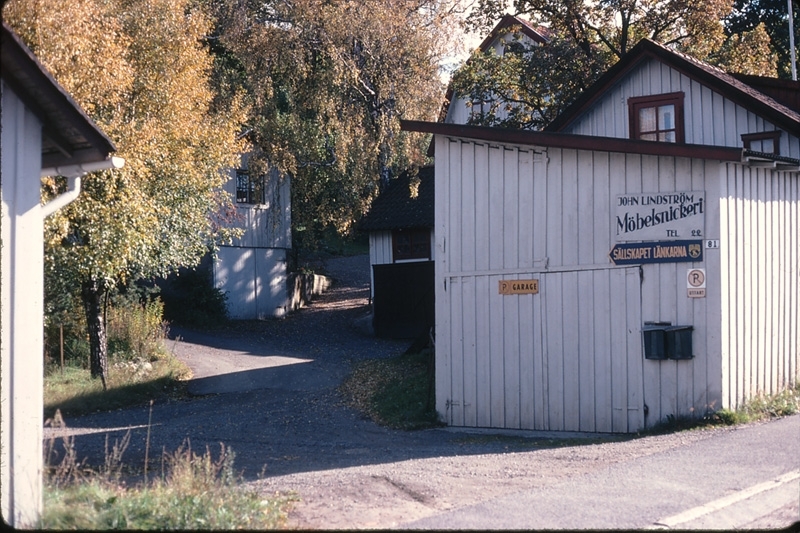 Gamla Riksvägen 79-81 år 1979. Till vänster ses uthuset till Sionkapellet. I mitten uppfarten till Högbo. Till höger John Lindström Möbelsnickeri.