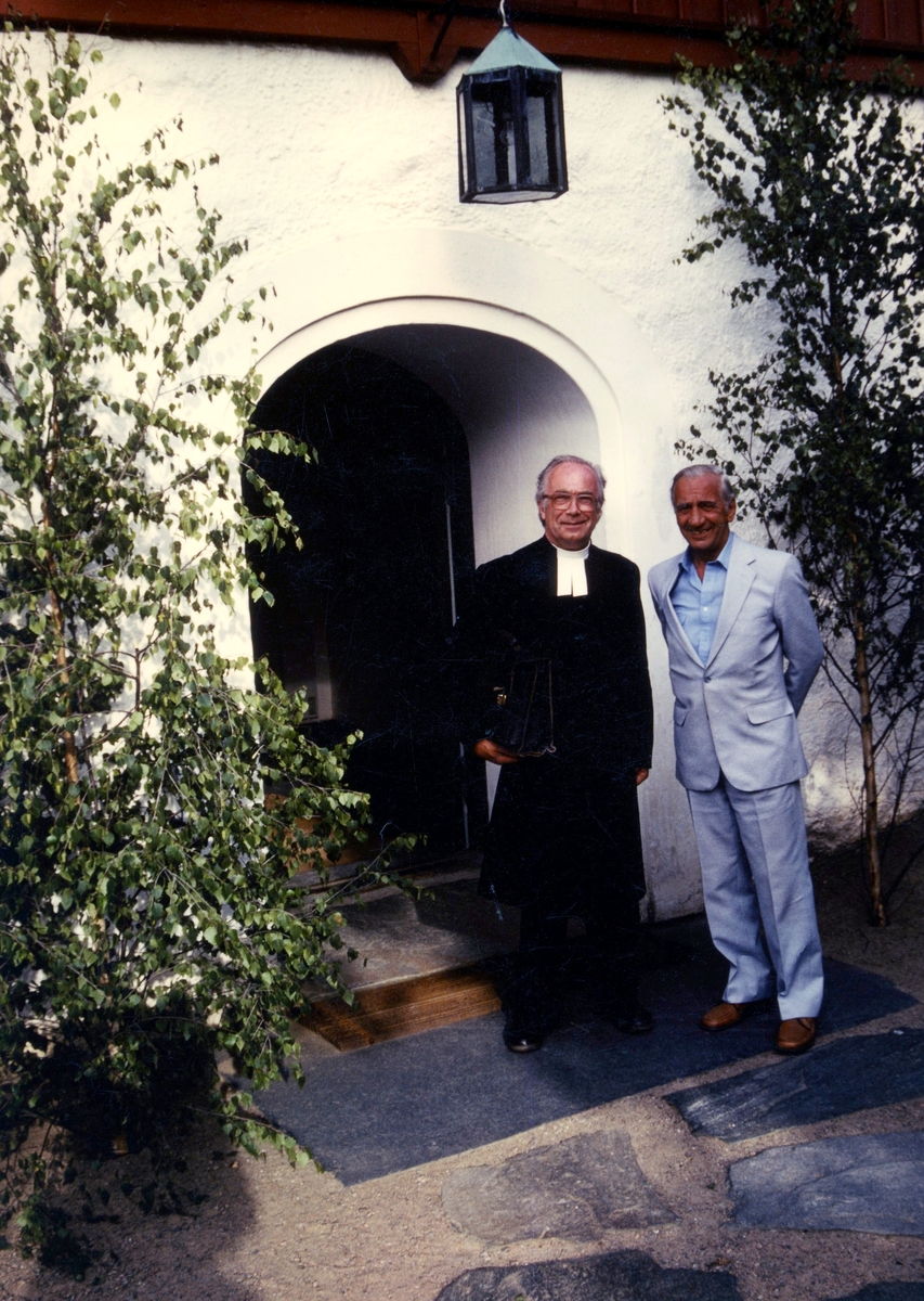 Komminister/Kyrkoherde Gustav Lindman och kyrkoråd/S-politiker i Kållered Elof Johansson står utanför Kållereds kyrka, 1980-tal.