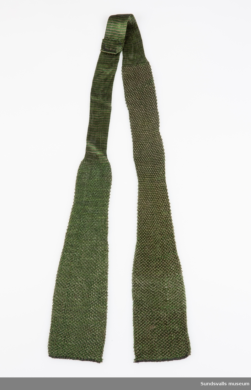Grön- och brunmönstrad slips i maskinvävd konstfiber.