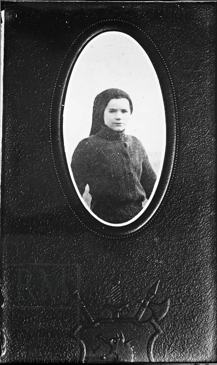 Portrett av ung jente i mørk drakt og hodeplagg.