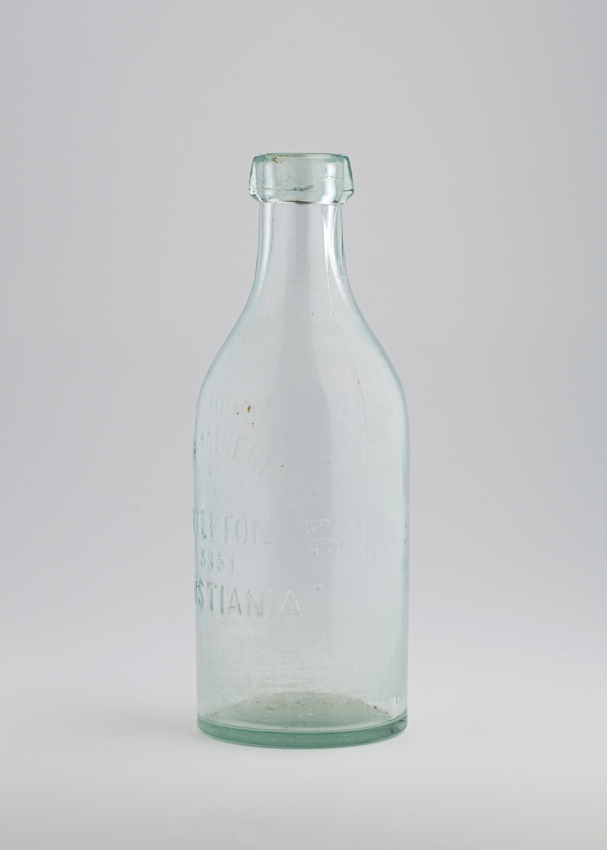 Liters melkeflaske som er høy og vid, og har et stort tut med kraftig kant rundt.