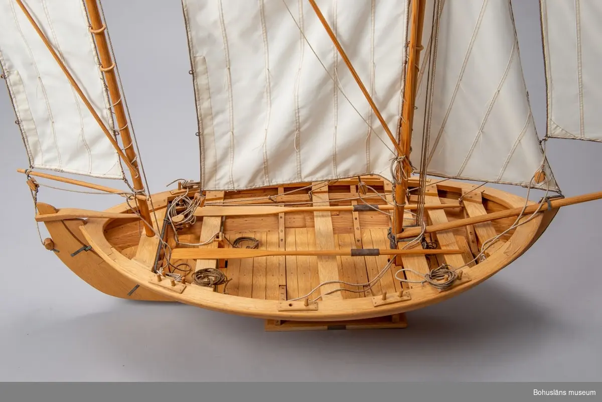 Detaljtrogen modell av en kåg med segel och åror. På stativet mässingsplakett med texten:
BPA BYGG AB
Uddevalla