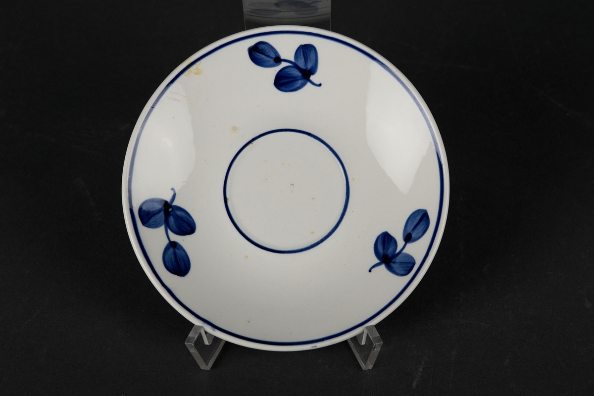 Hvitt tefat dekorert med en blå sirkel i midten, og en til langs kantene, og tre blå blomster.