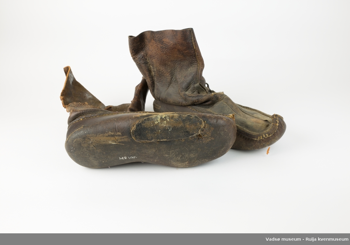 Brune lærsko av typen biekso (samisk). Den ene skoen er reparert under med påsydd lærlapp. Denne mangler også en del av ytterlæret høyere opp på skoen.