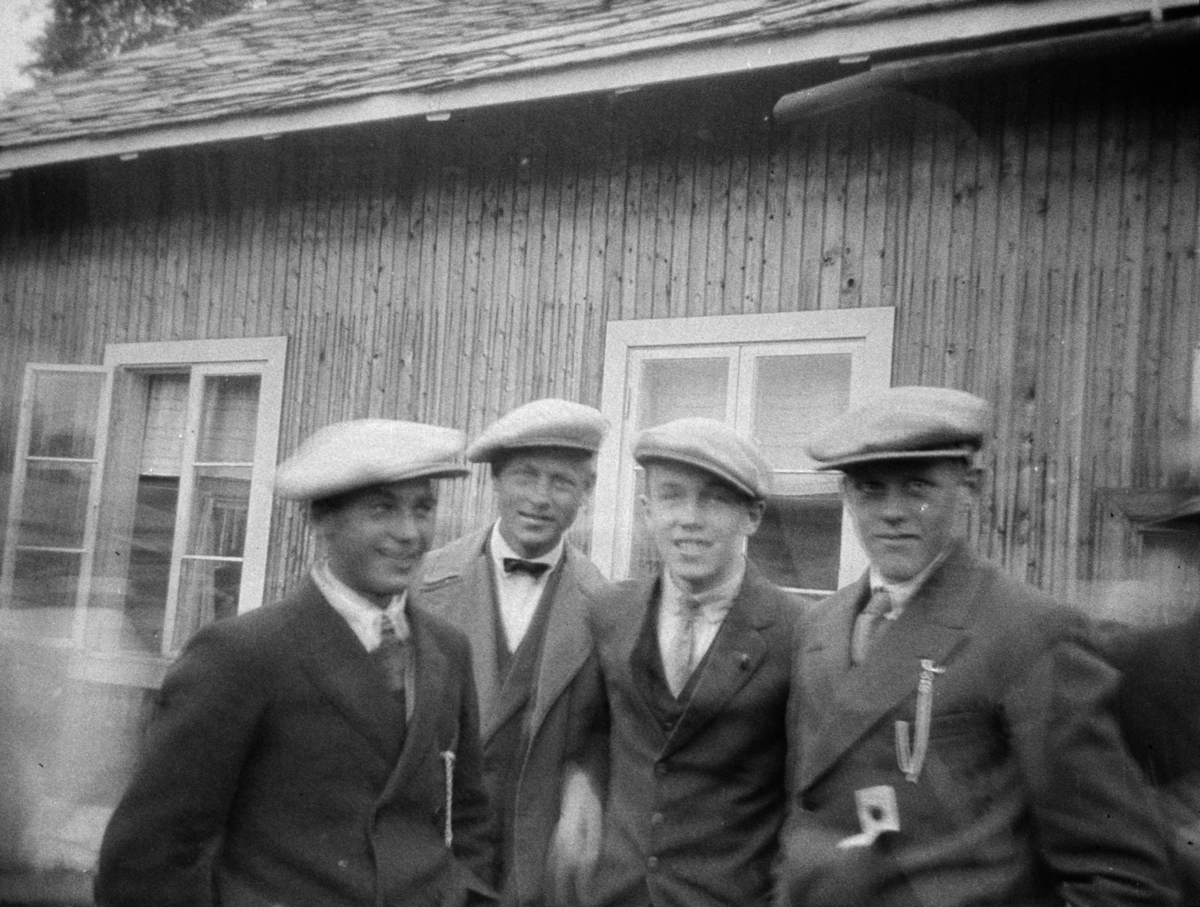 Fire unge gutter i skyggeluer utenfor ei hytte.