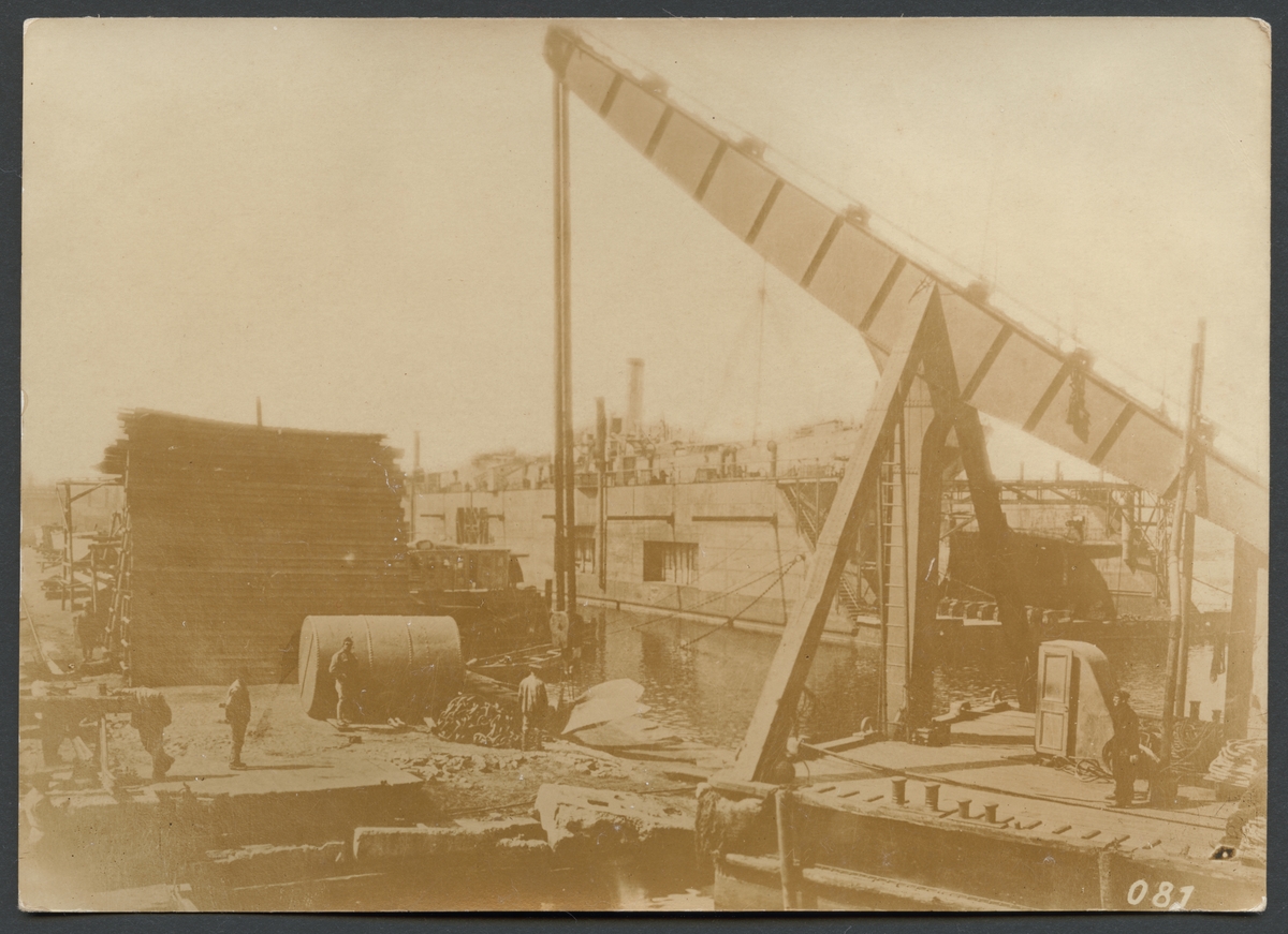 Bilden visar hamnarbetare på en kaj i Odessas hamn. Förgrunden domineras av en lyftkran och i bakgrunden syns en flytdocka.