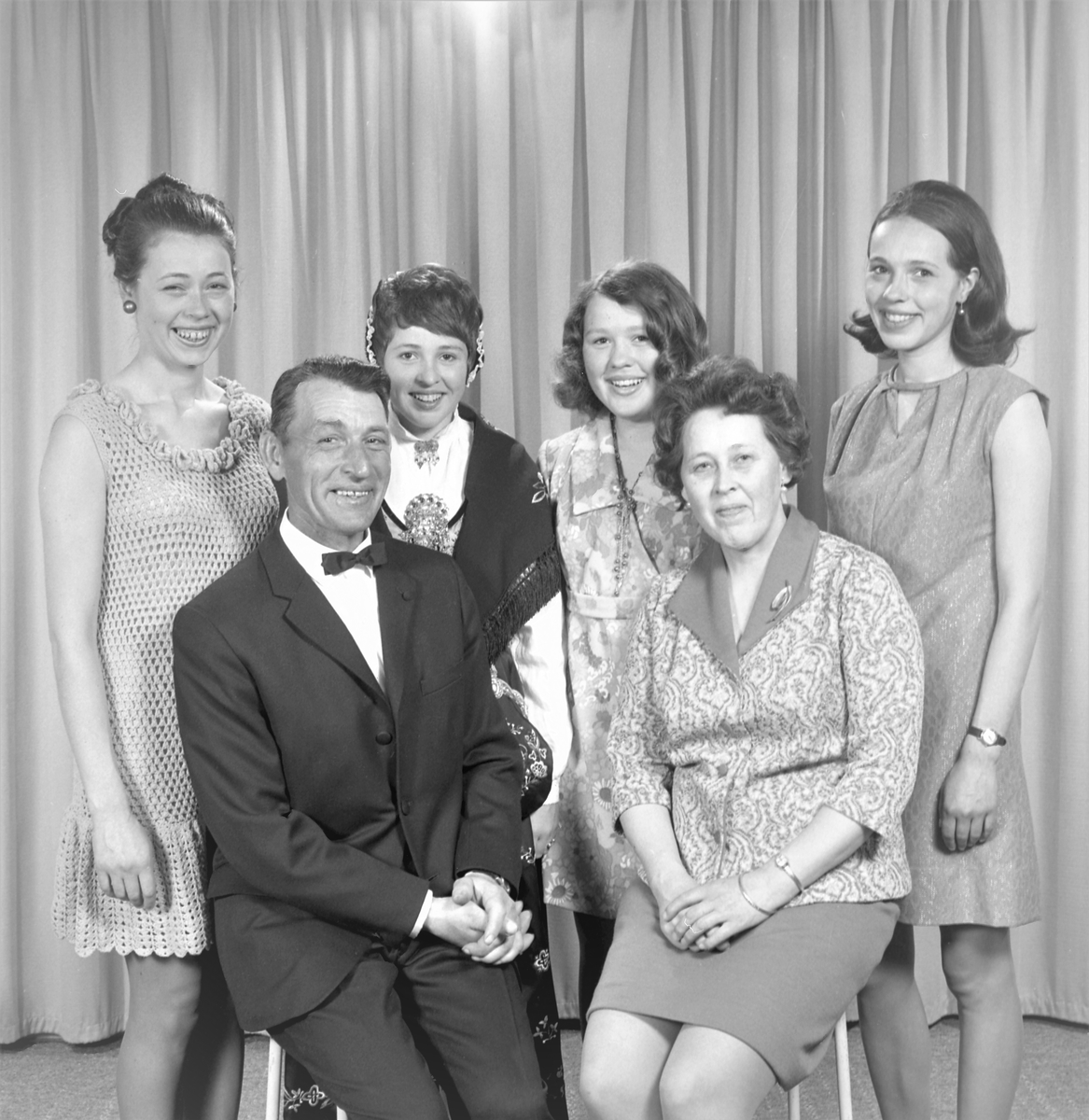 Portrett. Familiegruppe på seks. Mann, kvinne og fire unge kvinner, den ene i bunad. Bestilt av Odd Simonsen. Strandgt. 8